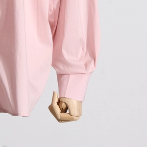 Dettaglio della manica di camicia rosa chiaro con eleganti pieghe e finiture curate