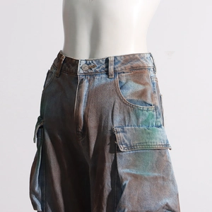 Close-up of cargo pockets and vintage acid-wash finish on loose fit graffiti denim pants