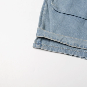 Detailed close-up of light blue denim cargo pocket with contrast stitching on a romper