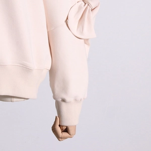 Detailed view of the oversized ribbon bow on the shoulder of this elegant apricot sweatshirt