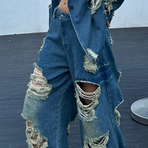 Dettaglio del tessuto denim blu scuro con bordi sfrangiati e lunghe nappine in stile grunge