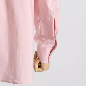 Dettaglio del polsino della camicia rosa con cuciture precise e tessuto in cotone liscio