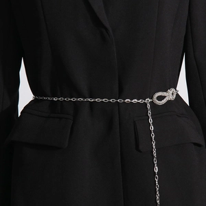 Detail of silver chain belt with rhinestone infinity knot buckle on black blazer