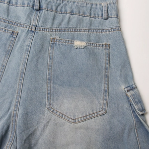 Detail view of light blue cargo jumpsuit pockets with distressed denim and topstitching