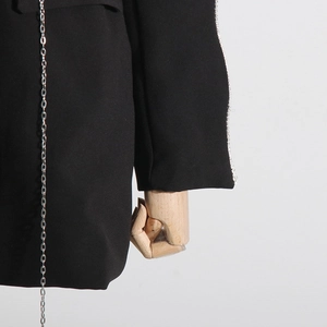 Detail of black blazer featuring hollow sleeve design with silver chains and rhinestones
