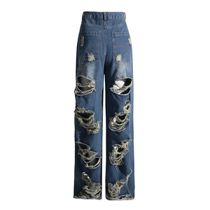Dettaglio macro delle tasche posteriori strappate e fori usurati sui jeans larghi