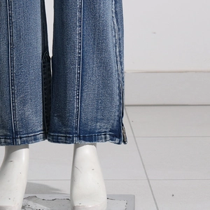 Detail of blue washed denim jeans showing side zipper slit and vertical seam stitching