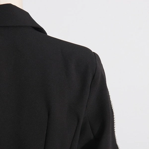 Close-up of sparkling rhinestone trim and woven fabric on black blazer shoulder