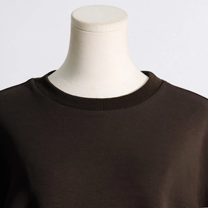 Close-up of ribbed crew neck and pleated bow stitching on dark brown sweatshirt