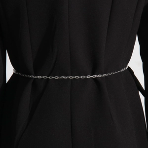 Detail of slim silver metal chain belt with oval links on a black suit jacket