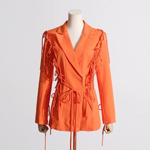 Détail du blazer orange vif avec rubans de taille ajustables et nœuds aux manches