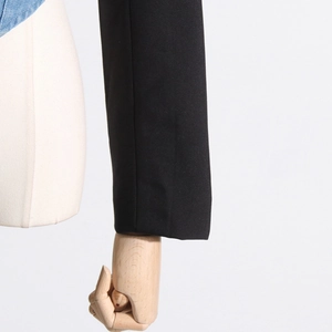 Detail of black woven sleeve and blue denim patchwork on a tailored jacket