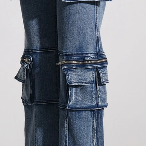 Macro detail of high-waist cargo jeans featuring 3D pockets and metal zippers