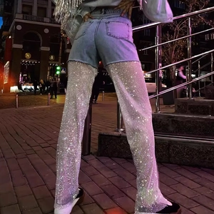 Close-up of sparkling rhinestone mesh leg sleeves and light blue denim shorts in city night