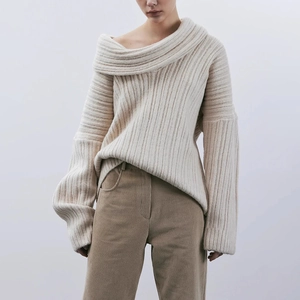 Close-up of off-shoulder asymmetric neckline on beige knitted sweater with rib textures