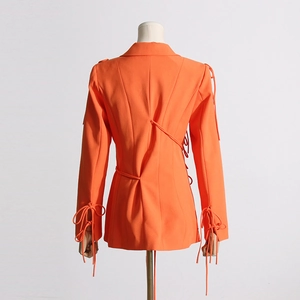 Détail du blazer orange avec des nœuds élégants au dos et une coupe cintrée