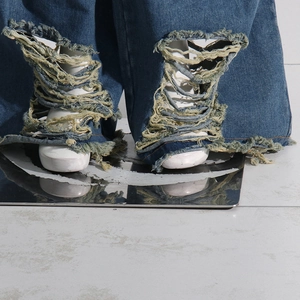 Dettaglio macro di jeans a gamba larga blu scuro con orlo strappato e stile street esagerato