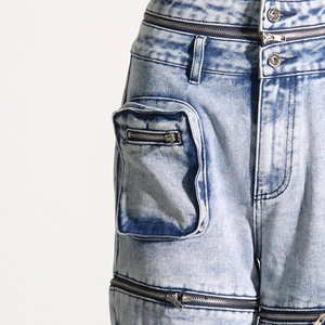 Détail du jean déconstruit avec zips multiples et texture denim au fini dégradé