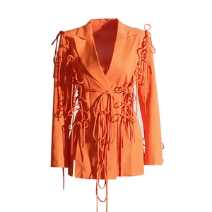 Détail du blazer orange vif avec des finitions complexes de cordons et de rubans noués