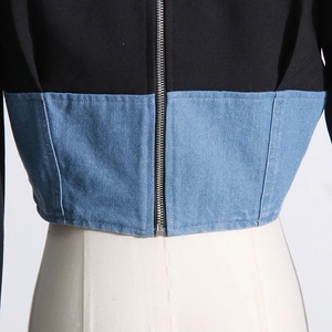 Detail of the silver metal zipper and denim patchwork on a black blazer jacket