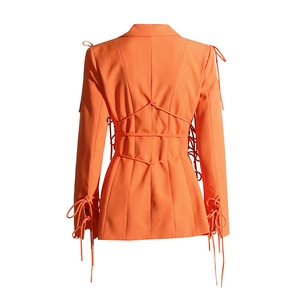 Détail du blazer orange avec laçage complexe au dos et coupe cintrée élégante