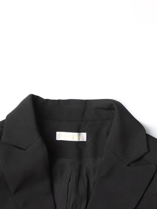 Detail of notched lapel and branded neck label on black tailored blazer jacket