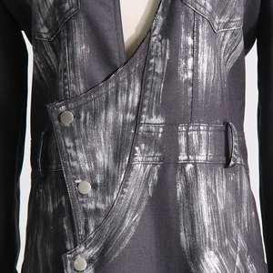 Gros plan sur le blazer noir asymétrique avec imprimé artistique argenté et boutons