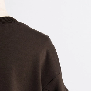 Detail view of smooth dark brown crewneck sweatshirt with pleated shoulder stitching