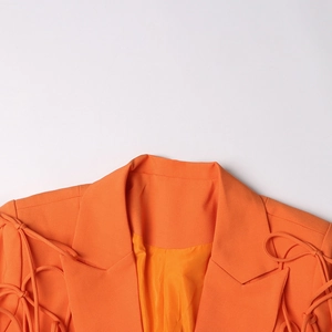 Détail du revers du blazer orange et décoration de ruban noué sur la manche chic
