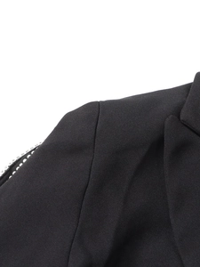 Detailed view of black blazer with sparkling rhinestone sleeve design and fabric texture