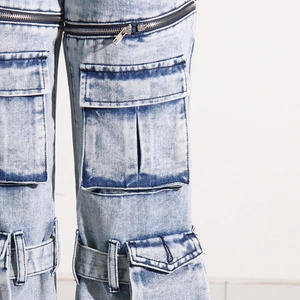 Détail d'un jean cargo délavé à l'acide avec fermetures éclair et poches utilitaires
