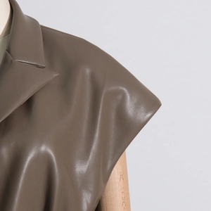 Dettaglio del gilet in ecopelle marrone con revers e morbida trama opaca