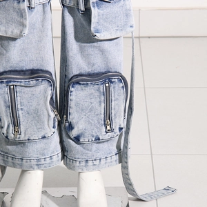 Détail d'un jean cargo délavé bleu clair avec poches zippées et rubans en denim