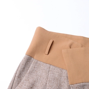 Detail view of high-waist camel patchwork and tweed texture on wide-leg trousers