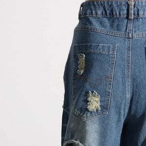 Dettaglio delle tasche posteriori in denim blu slavato con strappi e finiture usurate