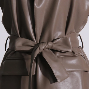Dettaglio di un gilet in ecopelle marrone scuro con elegante cintura annodata in vita