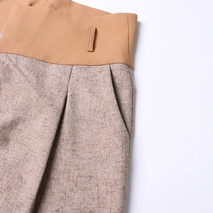 Detailed close-up of high-waisted trousers with contrast panels and functional side pockets