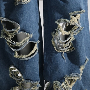 Dettaglio ravvicinato di jeans con strappi fatti a mano e texture con frange sottili