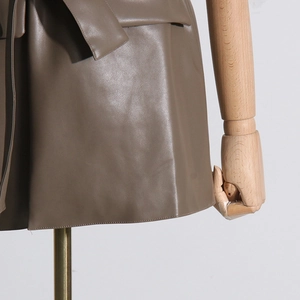 Dettaglio del gilet in ecopelle marrone con trama del tessuto, cintura e tasca a patta