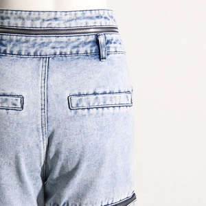 Gros plan détaillé du jean en denim délavé bleu clair avec zips à la taille