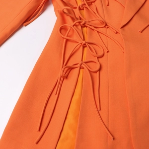 Détail du blazer orange élégant avec cordons de serrage latéraux et détails de nœuds