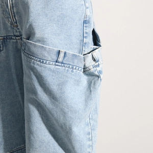 Détail d'un jean bleu clair montrant la texture sergé et les coutures de poche décoratives