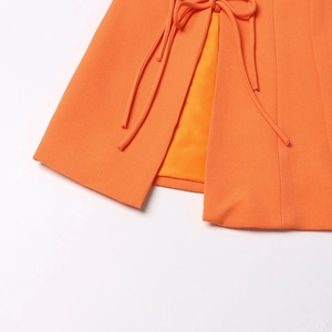 Détail du blazer orange vif avec nœud de taille réglable et doublure intérieure lisse