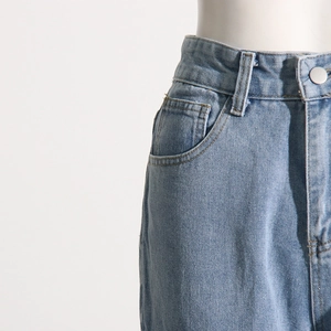 Detail of light blue denim waist with metal button and belt loops on casual pants
