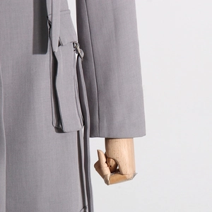 Detail eines grauen Blazers mit großer Pattentasche, Metallring und Fransen-Akzenten