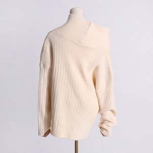 Close-up of cream chunky knit sweater featuring asymmetrical off-shoulder neckline