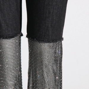 Close-up of sparkling silver rhinestone mesh patchwork on black denim straight jeans