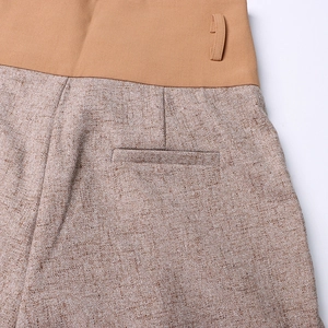 Close-up of high-waist patchwork wide leg pants showing tweed fabric and waist tie detail