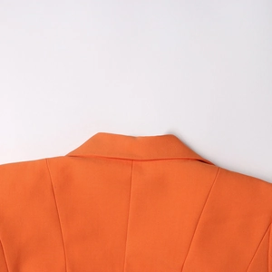 Détail du col à revers et des coutures d'épaule d'un blazer orange vif cintré