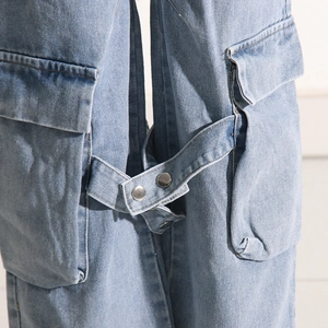 Detailed view of light blue denim cargo pants showing side flap pockets and metal buttons
